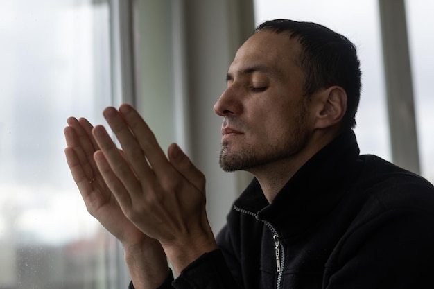 Young Caucasian man with closed eyes near the window