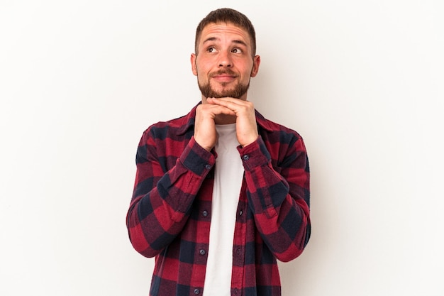 Young caucasian man with diastema isolated on white background keeps hands under chin, is looking happily aside.