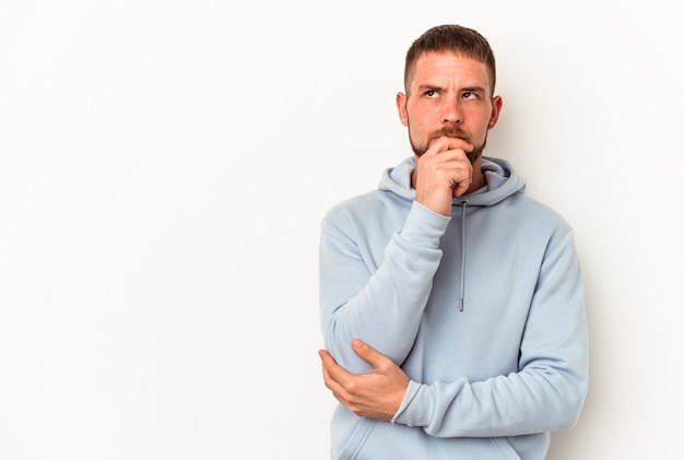 Young caucasian man with diastema isolated on white background looking sideways with doubtful and skeptical expression.