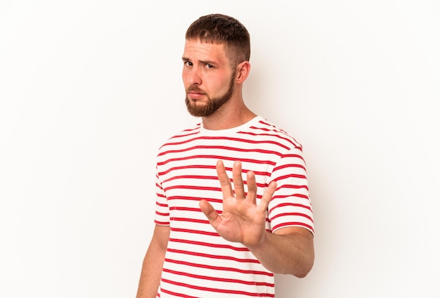 Young caucasian man with diastema isolated on white background rejecting someone showing a gesture of disgust.