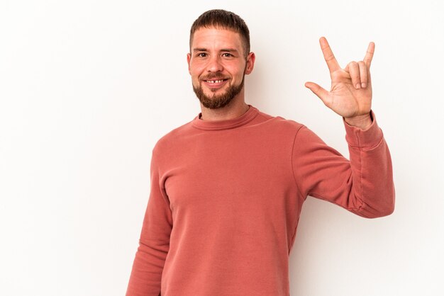 Young caucasian man with diastema isolated on white background showing a horns gesture as a revolution concept.