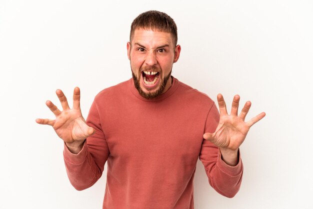 Young caucasian man with diastema isolated on white background upset screaming with tense hands.