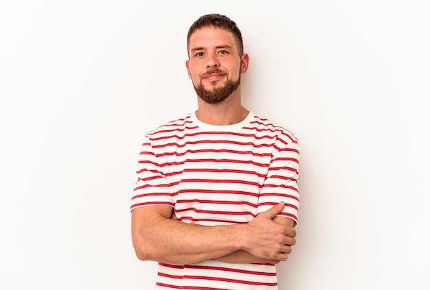 Foto giovane uomo caucasico con diastema isolato su sfondo bianco che si sente sicuro, incrociando le braccia con determinazione.