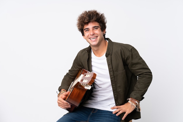 Young caucasian man with guitar over isolated white laughing