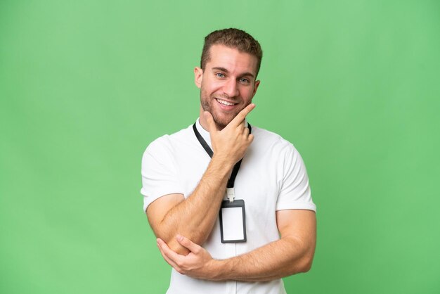 Young caucasian man with id card isolated on green chroma background happy and smiling