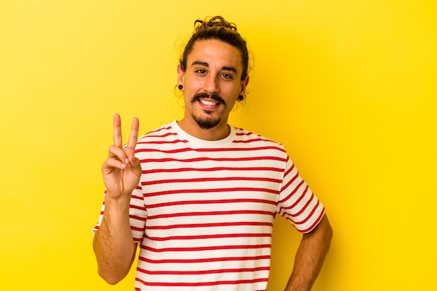 Young caucasian man with long hair isolated on yellow background showing number two with fingers.