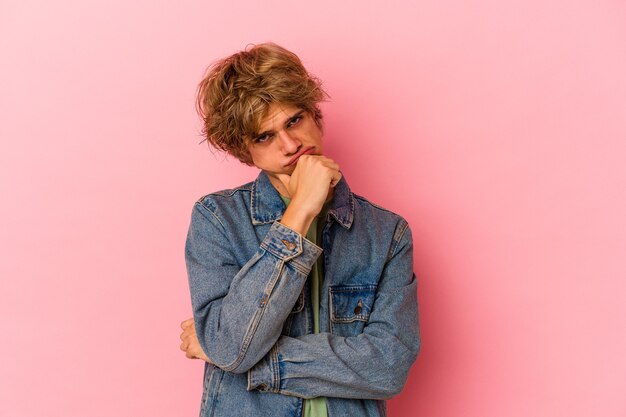 Young caucasian man with make up isolated on pink background tired of a repetitive task.