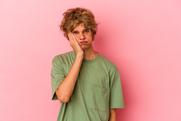 Young caucasian man with make up isolated on pink background who feels sad and pensive, looking at copy space.