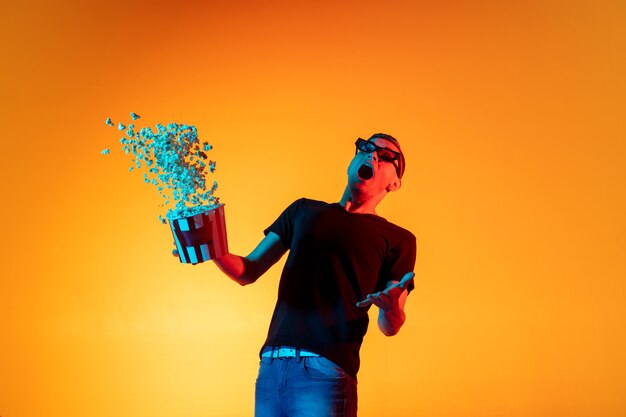 Young Caucasian man with microphone isolated over orange studio background in neon light