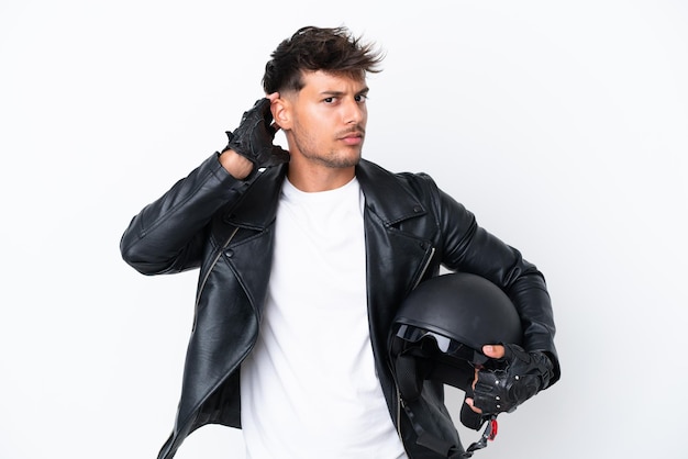 Young caucasian man with a motorcycle helmet isolated on white background having doubts