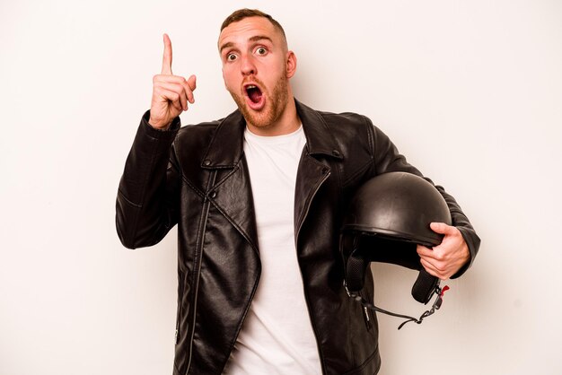Young caucasian man with a motorcycle helmet isolated on white background having an idea inspiration concept