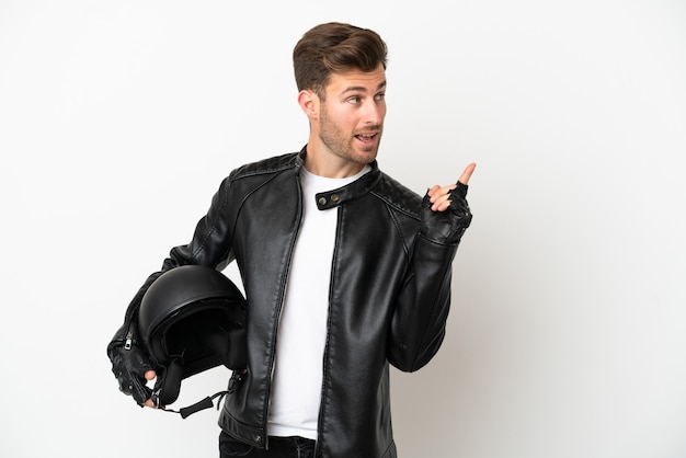 Молодой кавказец в мотоциклетном шлеме на белом фоне, намереваясь реализовать решение, подняв палец вверх