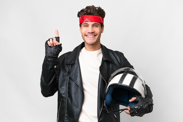 Young caucasian man with a motorcycle helmet over isolated white background pointing up a great idea