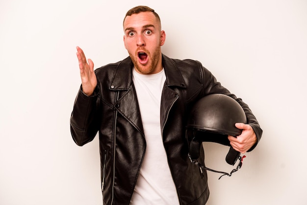 Young caucasian man with a motorcycle helmet isolated on white background surprised and shocked