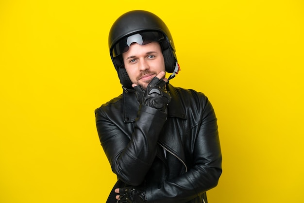 Young caucasian man with a motorcycle helmet isolated on yellow background happy and smiling