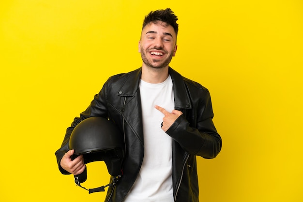 놀란 표정으로 노란색 배경에 격리된 오토바이 헬멧을 쓴 백인 청년
