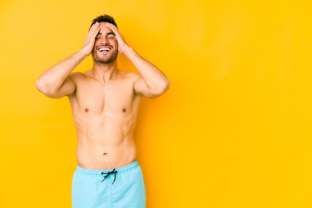 Young caucasian man with swimsuit isolated on yellow