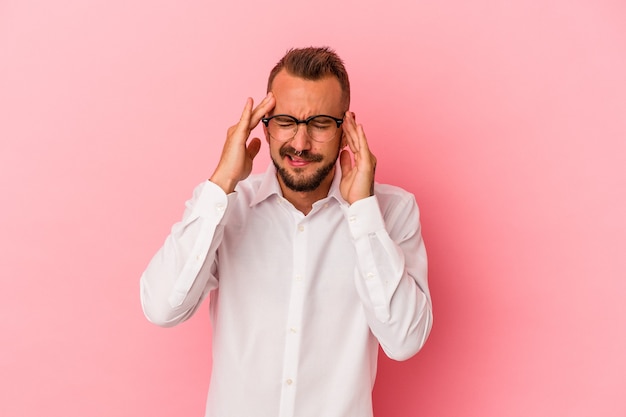 Young caucasian man with tattoos isolated on pink background  having a head ache, touching front of the face.