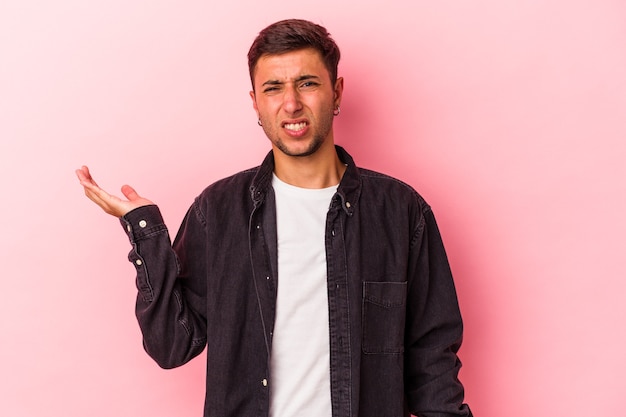 Young caucasian man with tattoos isolated on yellow background  doubting and shrugging shoulders in questioning gesture.