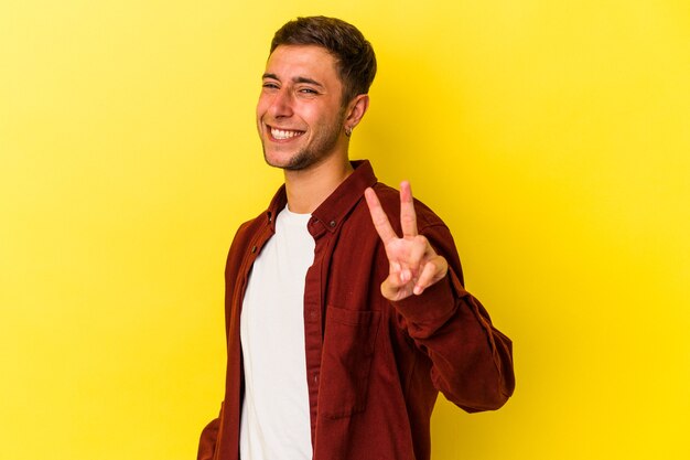 Young caucasian man with tattoos isolated on yellow background  showing number two with fingers.