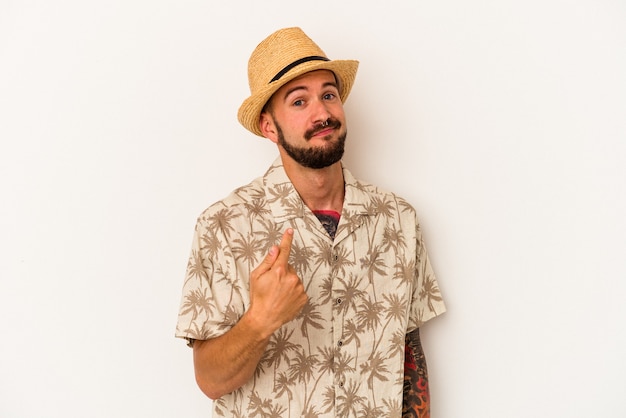 Young caucasian man with tattoos wearing summer clothes isolated on white background  pointing with finger at you as if inviting come closer.