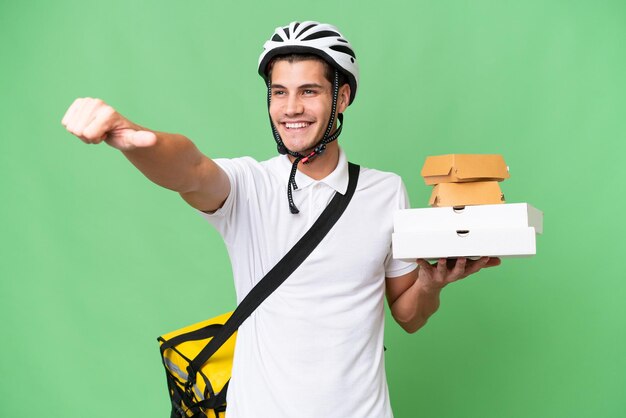 Young caucasian man with thermal backpack over isolated background giving a thumbs up gesture