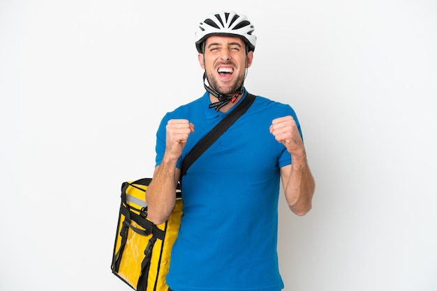 Young caucasian man with thermal backpack isolated on white background celebrating a victory in winner position