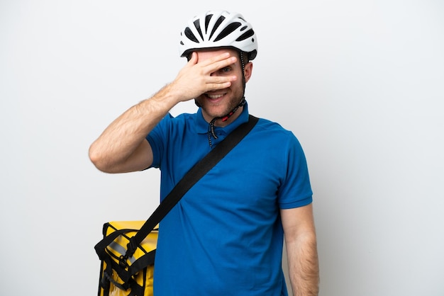 Young caucasian man with thermal backpack isolated on white background covering eyes by hands and smiling