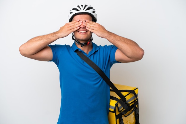 Young caucasian man with thermal backpack isolated on white background covering eyes by hands