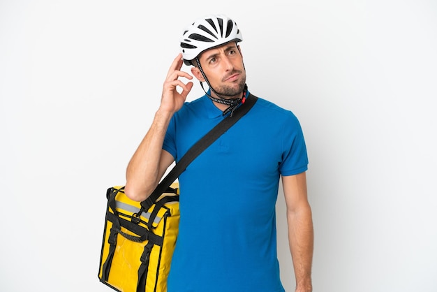 Young caucasian man with thermal backpack isolated on white background having doubts