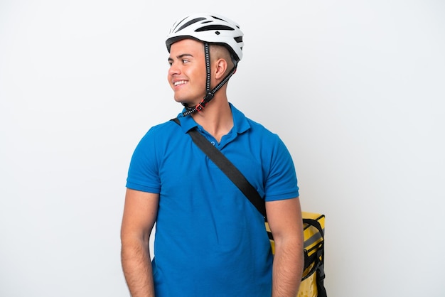 Young caucasian man with thermal backpack isolated on white background looking side