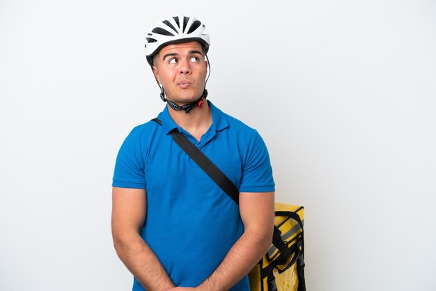 Young caucasian man with thermal backpack isolated on white background and looking up