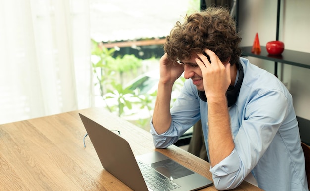 Foto il giovane uomo caucasico lavora da casa sul laptop e si connette online all'ufficio al chiuso per il posto di lavoro internet remoto