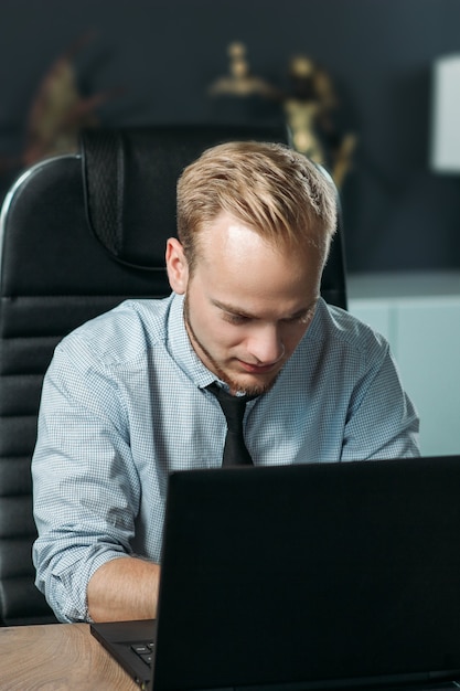 young caucasian man working in the office with a laptop the concept of an employee of European