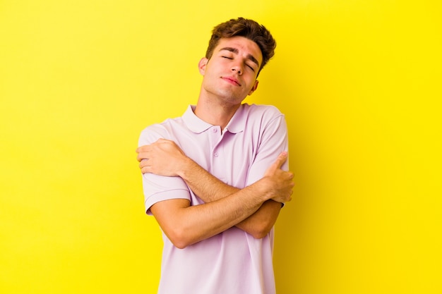 Young caucasian man on yellow hugs, smiling carefree and happy.