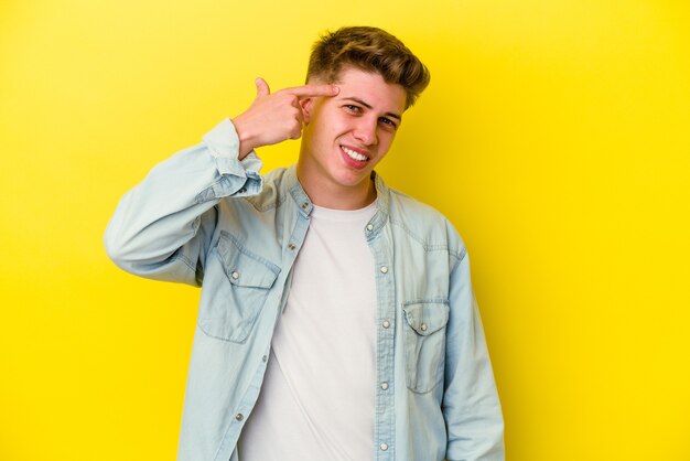 Young caucasian man on yellow showing a disappointment gesture with forefinger.