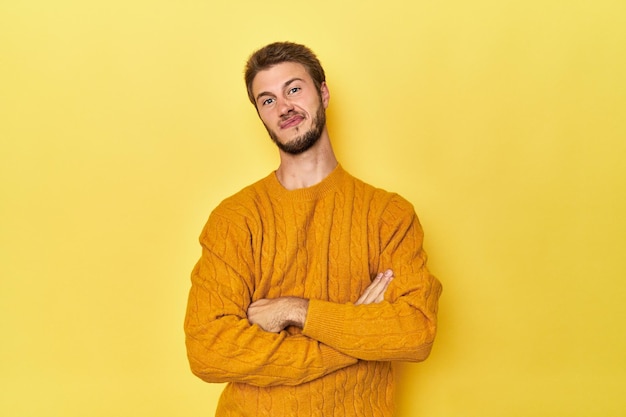 Young caucasian man on a yellow studio background suspicious uncertain examining you