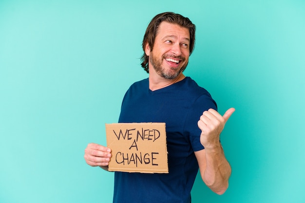 Young caucasian middle age man holding a We need a change placard on blue