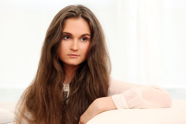 Photo young caucasian moman with long hair sitting on a coach