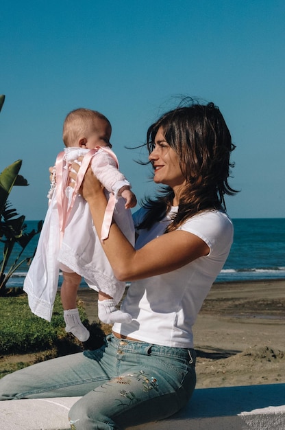 Young Caucasian mother with baby in her arms by the sea