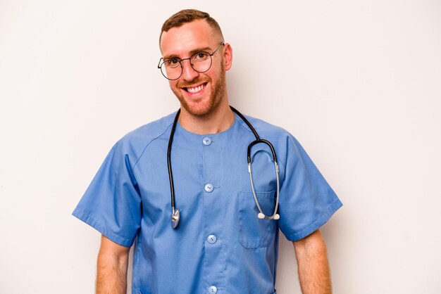 Young caucasian nurse man isolated on white background happy smiling and cheerful