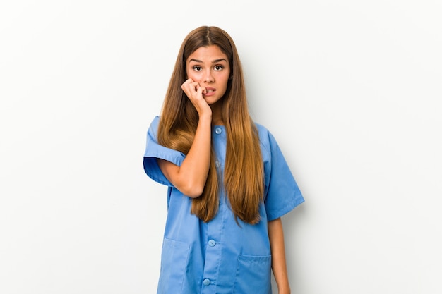 Young caucasian nurse woman biting fingernails, nervous and very anxious.