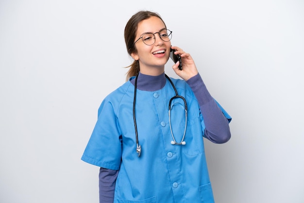 Young caucasian nurse woman isolated on white background keeping a conversation with the mobile phone