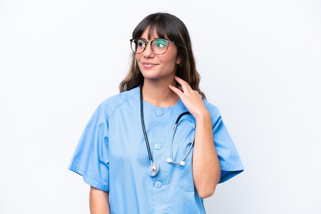 Young caucasian nurse woman isolated on white background looking up while smiling