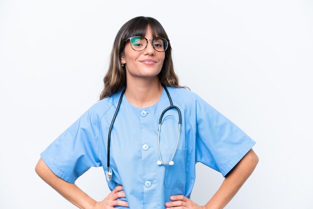 Young caucasian nurse woman isolated on white background posing with arms at hip and smiling