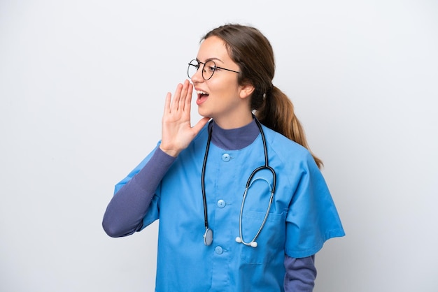 Young caucasian nurse woman isolated on white background shouting with mouth wide open to the lateral