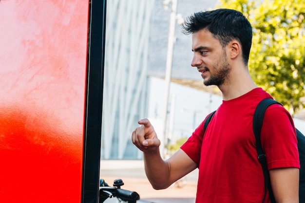 Foto giovane impiegato caucasico che noleggia una bicicletta su un touch screen rosso