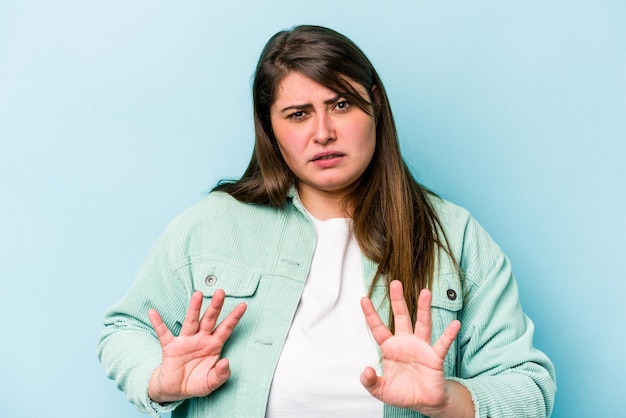 Foto giovane donna caucasica sovrappeso isolata su sfondo blu che rifiuta qualcuno che mostra un gesto di disgusto