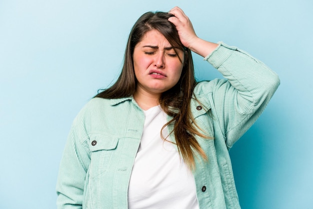 Young caucasian overweight woman isolated on blue background tired and very sleepy keeping hand on head