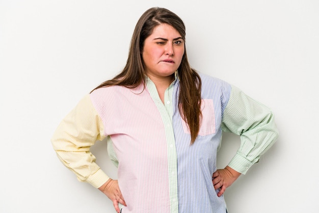 Young caucasian overweight woman isolated on white background frowning face in displeasure, keeps arms folded.